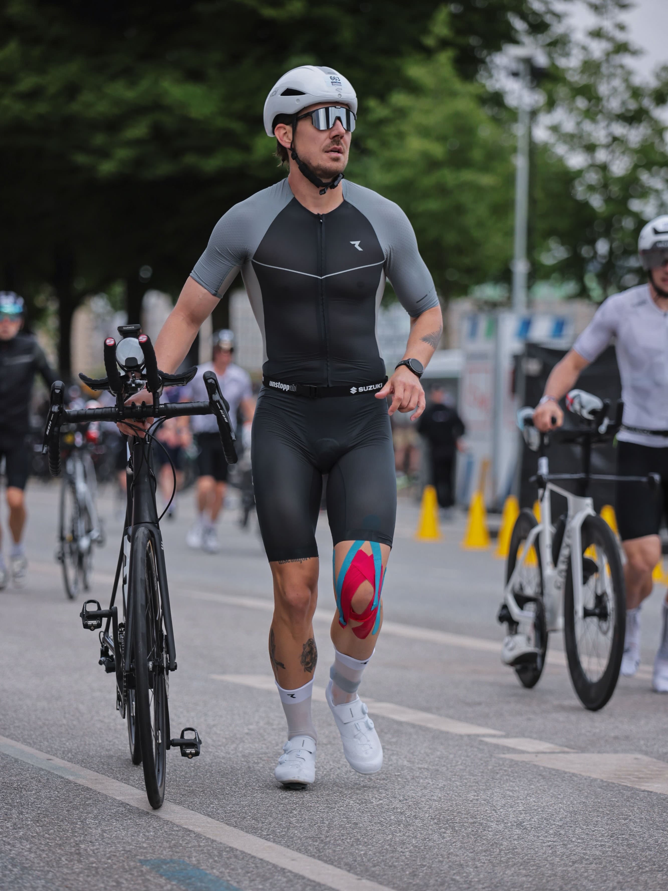 Adrian walking his bike through transition at IRONMAN Hamburg.